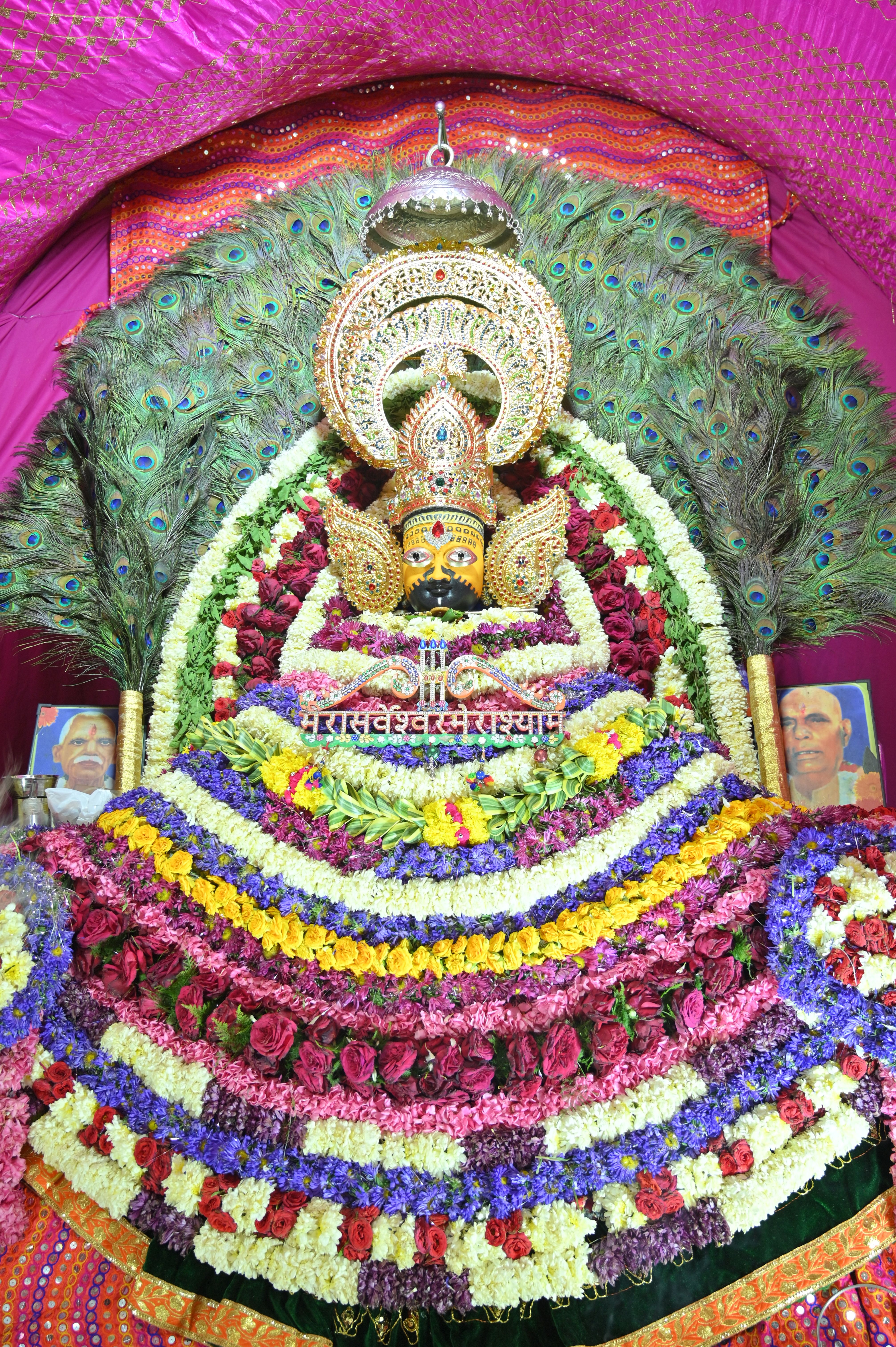 Colorful and intricate Hindu deity decoration adorned with peacock feathers and flowers in Patiala, India.
