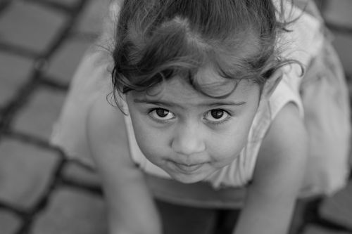 Free Artistic black and white close-up of a child with expressive eyes and innocent expression outdoors. Stock Photo