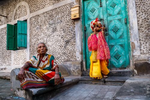 Free A colorful cultural scene in Kolkata featuring a child in traditional attire posing beside an elderly woman. Stock Photo
