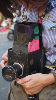A woman holding a vintage camera, showcasing retro photography amidst an urban backdrop.