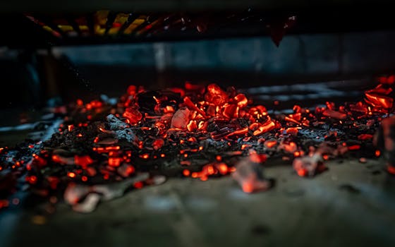 Close-up of glowing coals in a grill, highlighting the intense heat and vibrant colors.
