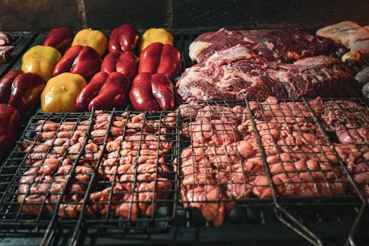 Assorted meats and peppers being grilled over charcoal, capturing a rustic barbecue experience.
