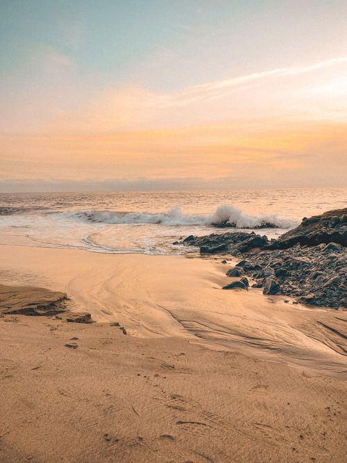 Free Tranquil scene of Laguna Beach at sunrise with gentle waves and golden sand. Stock Photo
