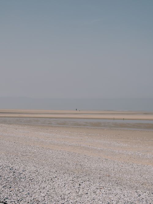 Free Serene and vast beach with a pebbled shore under a clear sky, perfect for relaxation. Stock Photo