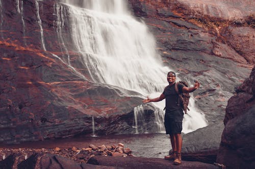 滝の近くに立っている男の写真
