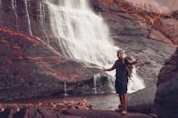 一位快乐的徒步旅行者在雄伟的瀑布旁摆姿势，捕捉冒险与自然的精髓