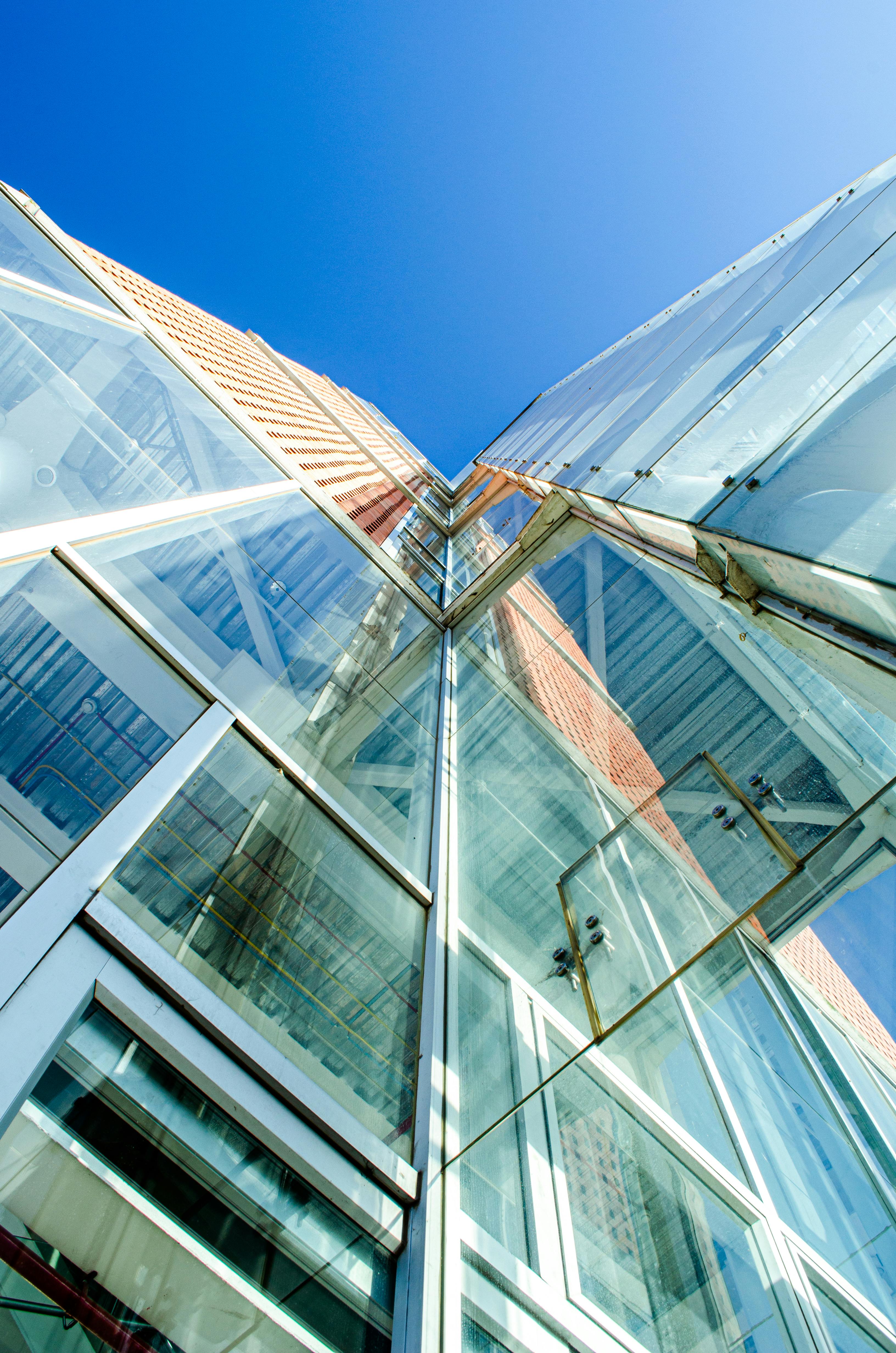 Upward angle view of a modern glass skyscraper reflecting the clear blue sky in Cuenca, Ecuador.