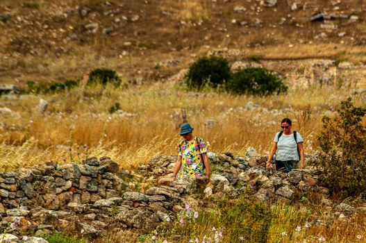 A couple hiking through the stone ruins in Pamukkale, Türkiye on a sunny day.