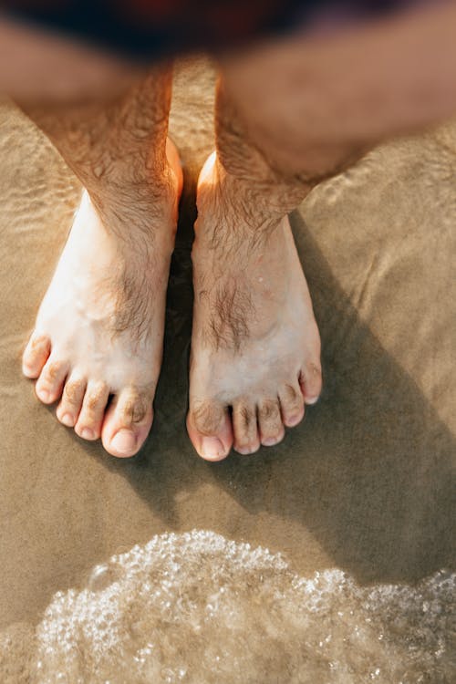 Feet of Man Standing on Beach