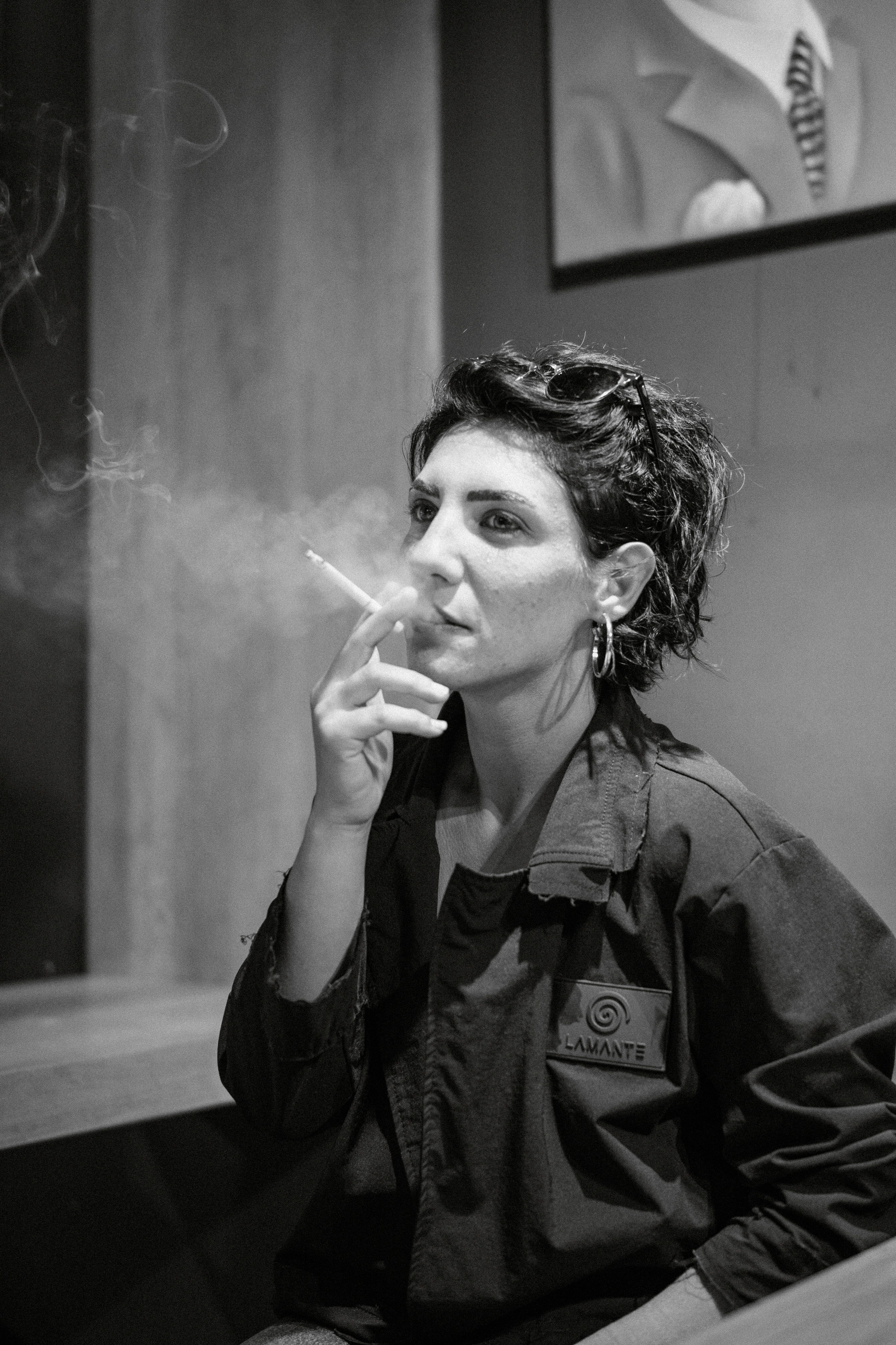 Black and white portrait of a woman smoking indoors, exuding a moody and artistic vibe.