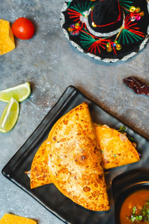 Free Captivating top view of freshly made tacos alongside a colorful Mexican hat on a gray background. Stock Photo