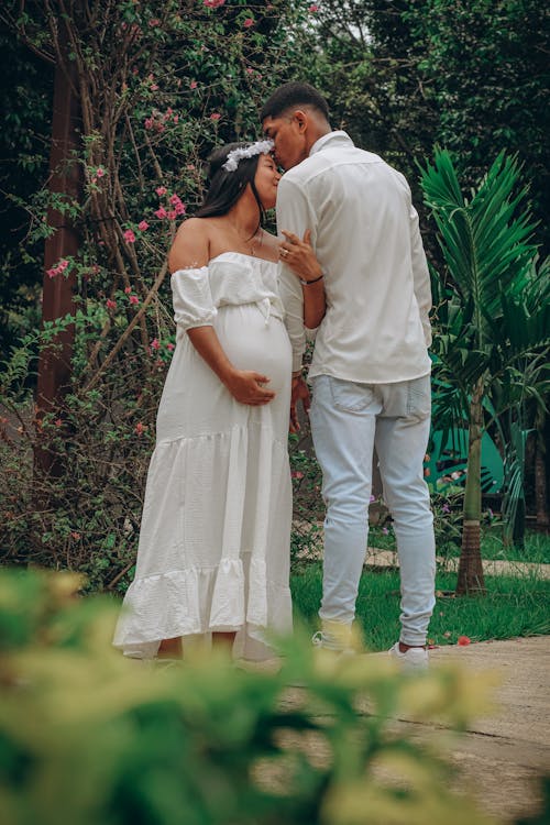 A Pregnant Woman and a Man Standing in a Park 