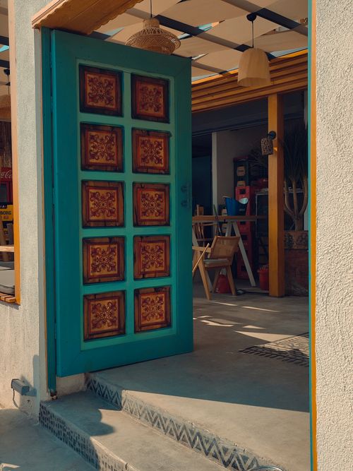 Free An inviting open door leading to a sunlit, artistic workspace with vibrant and intricate designs. Stock Photo