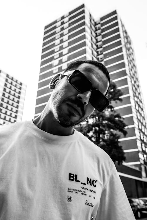 Man in Shades Stands against Skyscraper