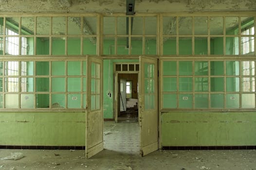Decaying interior of an abandoned building with peeling mint green paint and glass panel doors.
