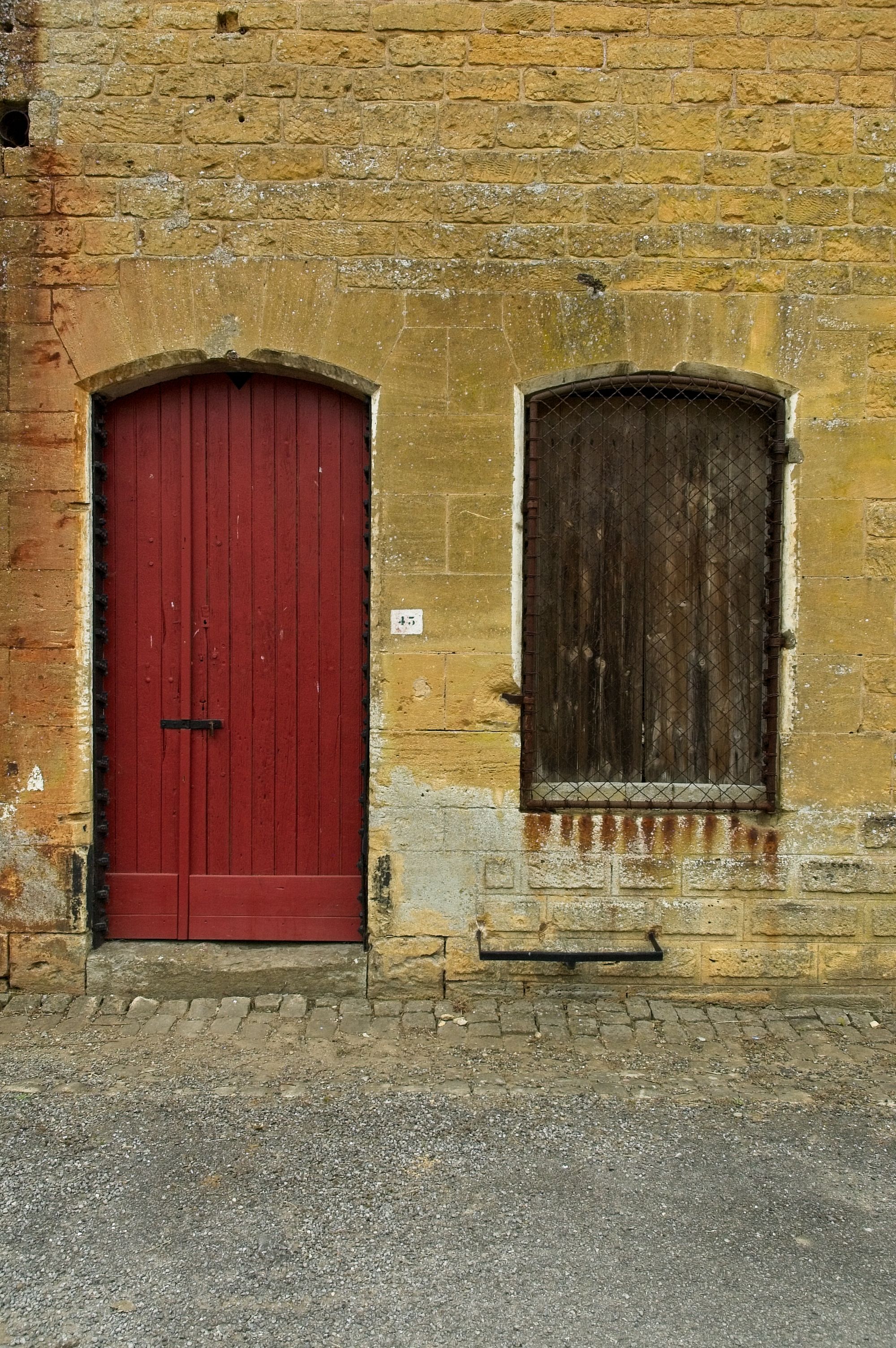 Red Wooden Door and a Barred Window in an Old Building · Free Stock Photo