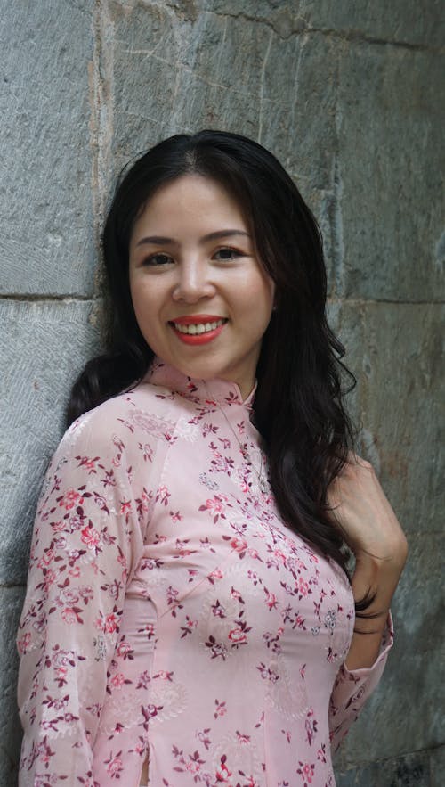 Young Woman in a Pink Dress Standing against the Wall and Smiling