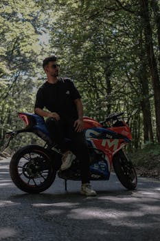 Man on motorcycle in a serene forest setting, exuding a sense of adventure and style.