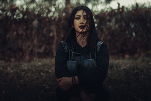 Free A young woman in a black outfit and lipstick sitting outdoors in Tehran, Iran. Stock Photo