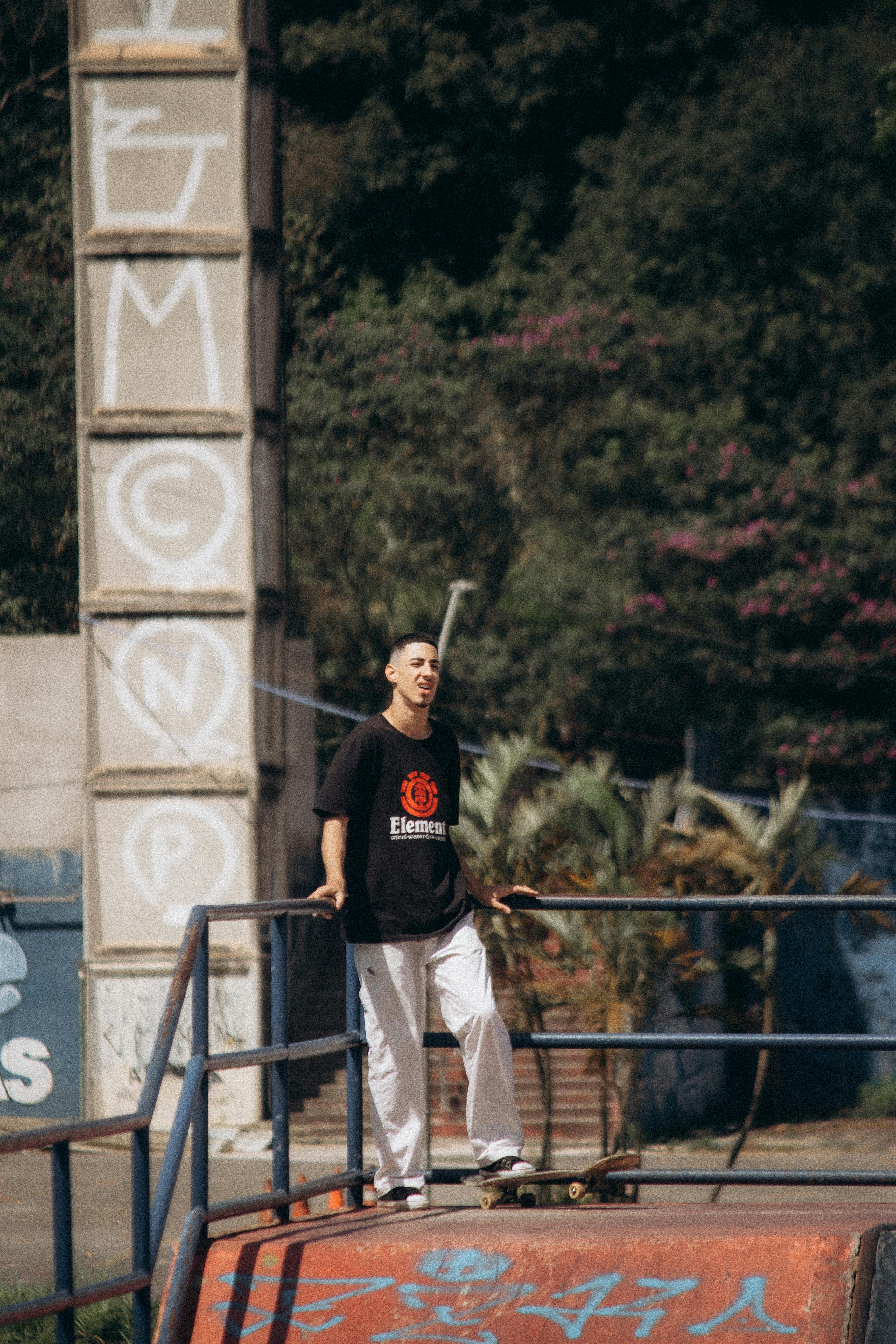A young man standing on a skateboard in an urban skatepark on a sunny day.