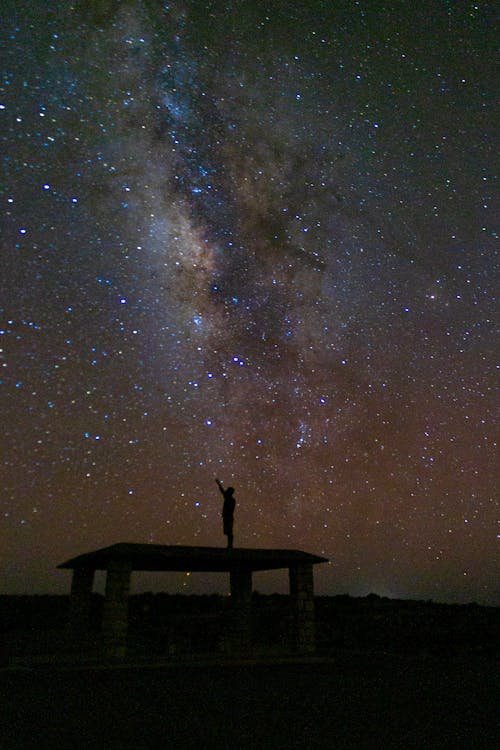 Free Person Standing on Platform under Clear Sky with Stars Stock Photo