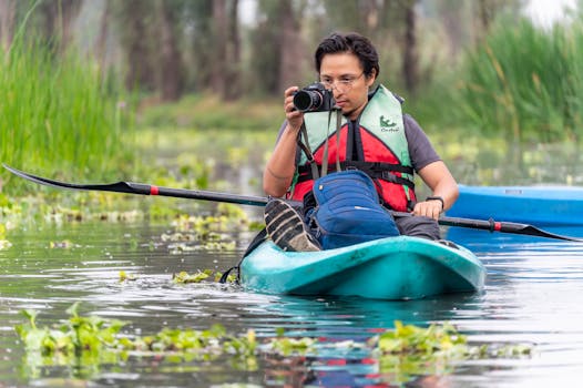 A young man on a kayaking adventure in CDMX, México, capturing nature with his camera.