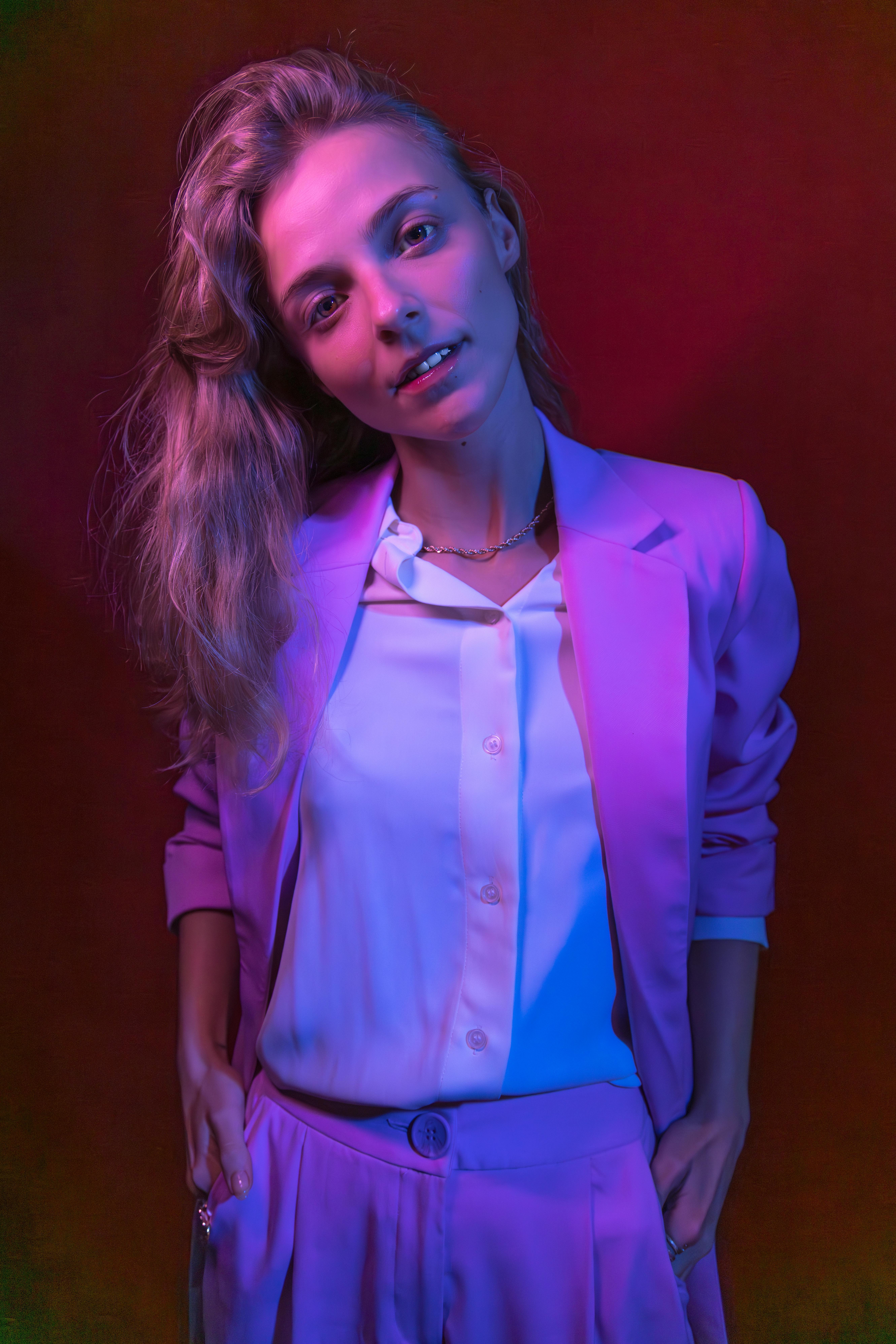 Creative portrait of a young woman in vibrant colored lighting and fashionable attire.