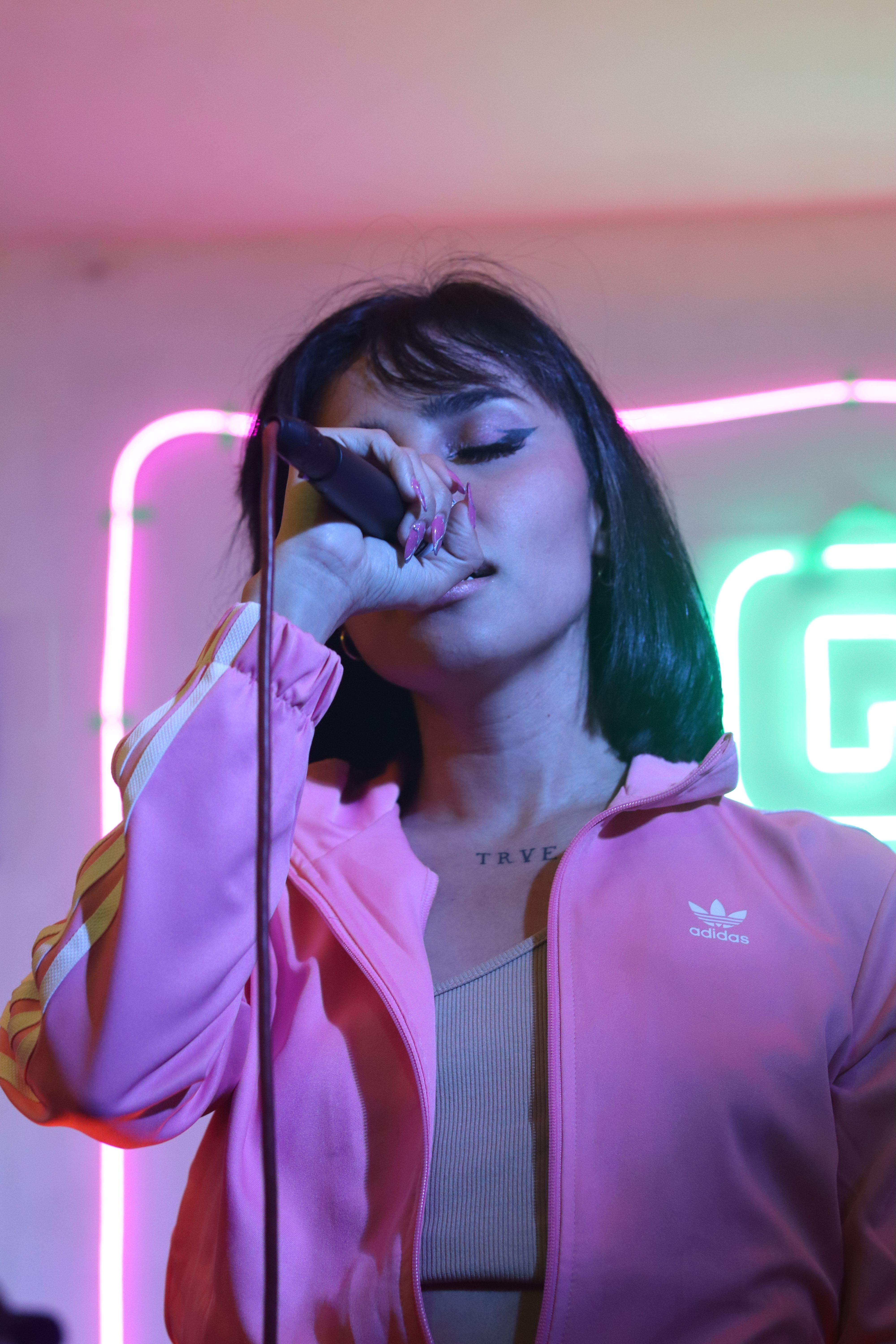 Vibrant image of a female singer passionately performing on stage with neon lights. - Karaoke Nights in Barbados: The Best Bars to Sing Your Heart Out