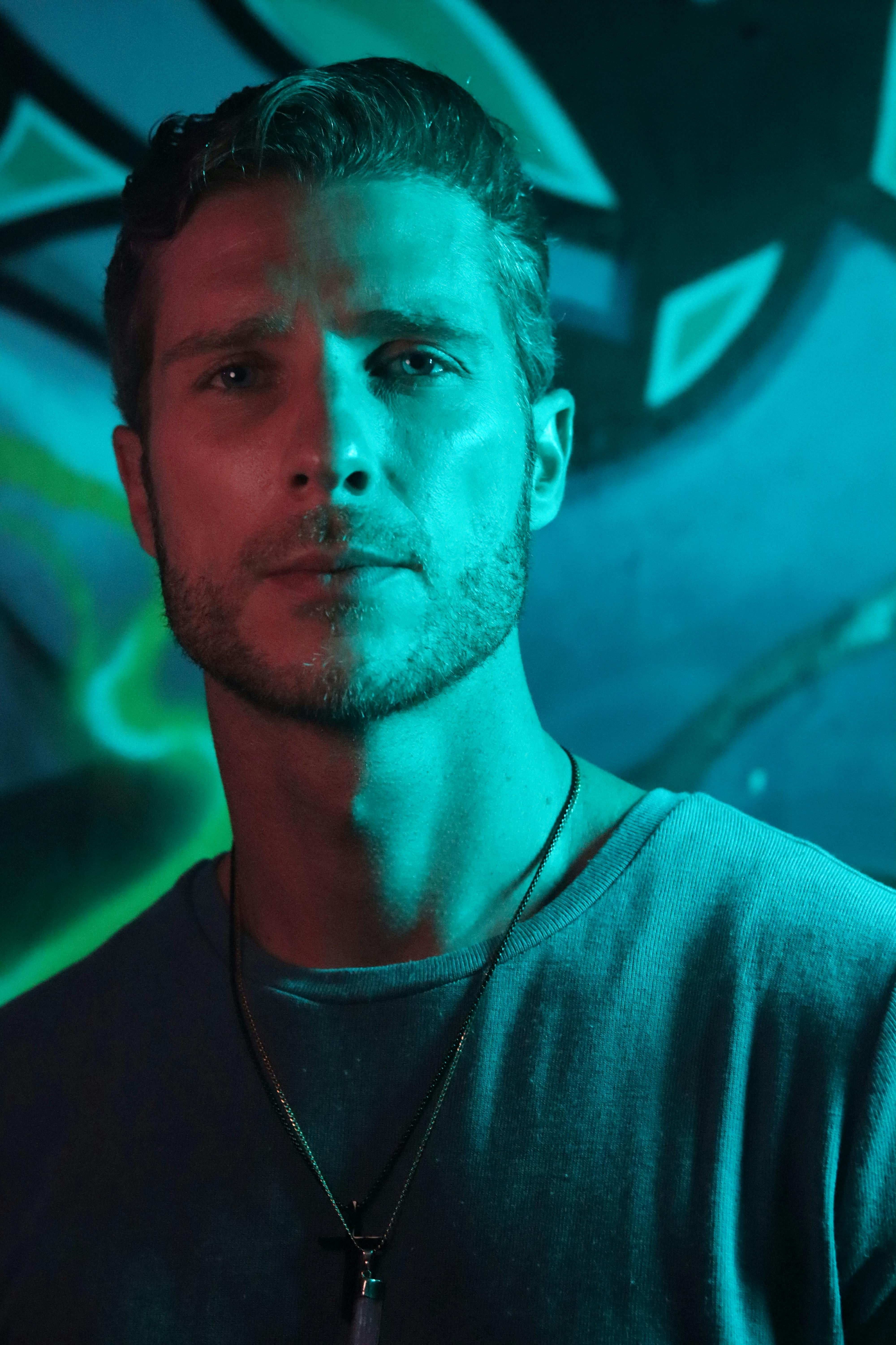 Striking urban portrait of a man with a necklace under moody lighting.