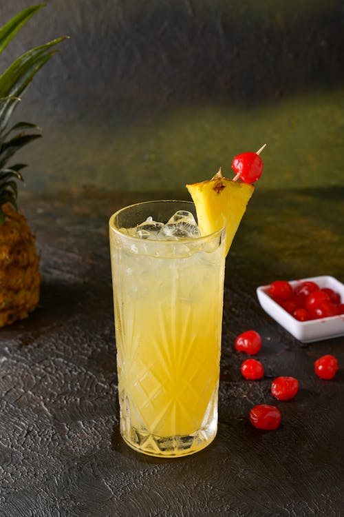 Free Cocktail in Collins Glass Decorated with Pineapple and Pickled Cherries Stock Photo