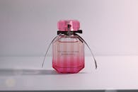 粉色香水瓶时尚别致，白色瓶身上饰有蝴蝶结，瓶盖设计精巧复杂