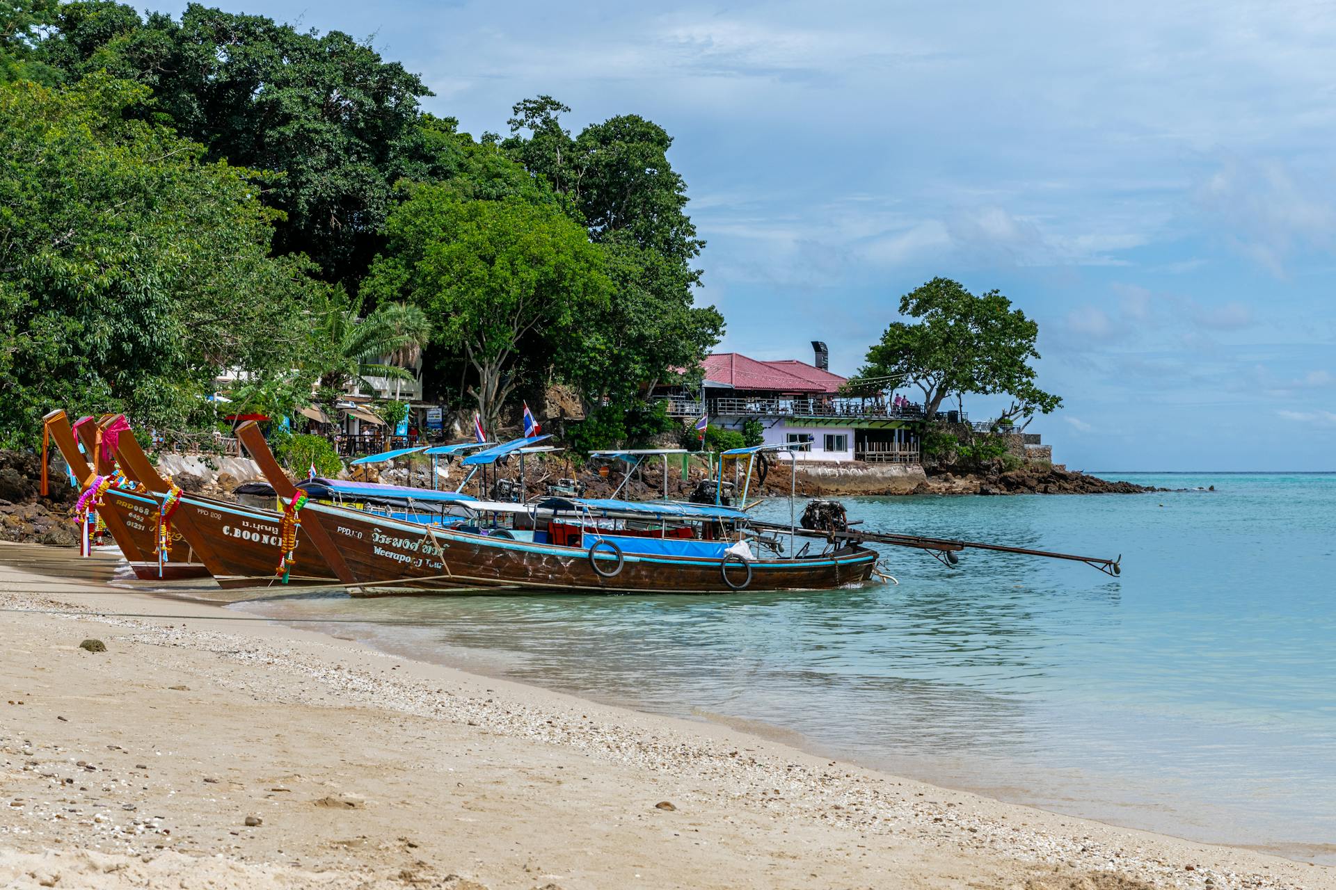 Colorful longtail boats moored on the serene beach of Phuket, Thailand.