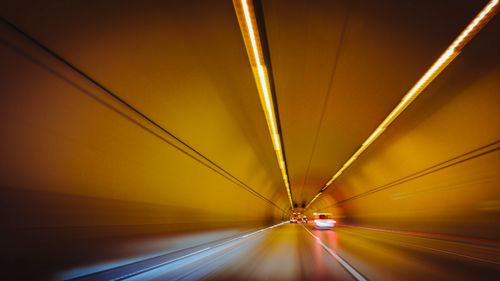 Free Captivating view of cars speeding through a brightly lit tunnel at night, showcasing motion blur and dynamic light trails. Stock Photo
