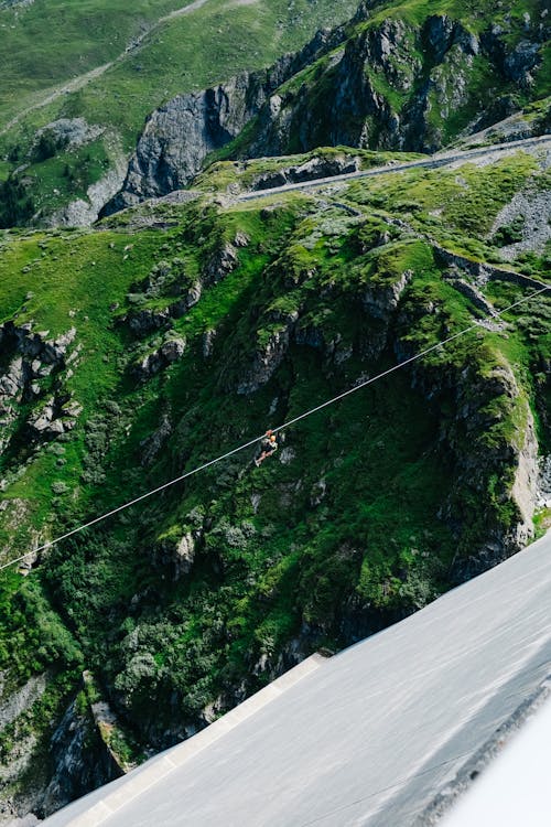 Person Riding Zip Line above Mountain Valley