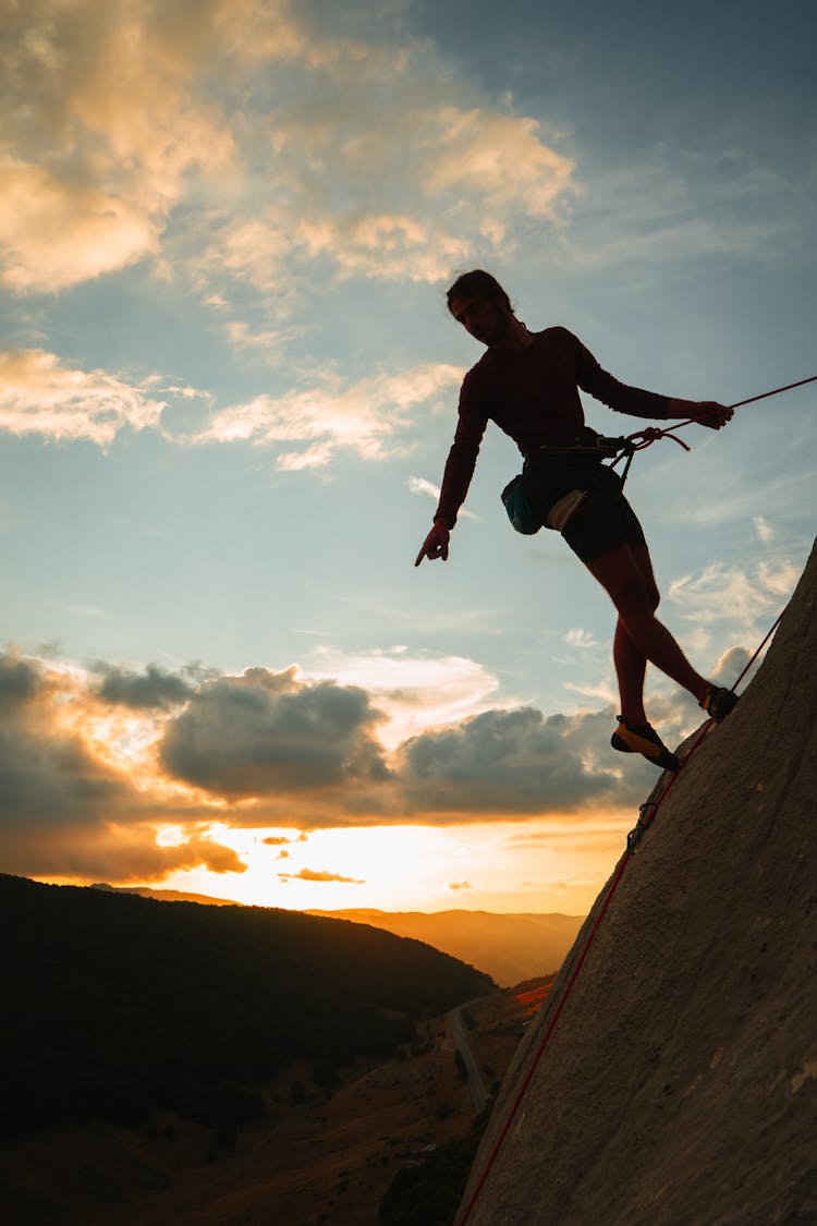 Silhouette Of A Climber On A Cliff At Dusk