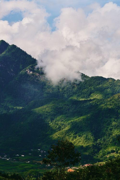 Free A picturesque landscape of green hills, clouds, and a rural village in Lào Cai, Vietnam. Stock Photo