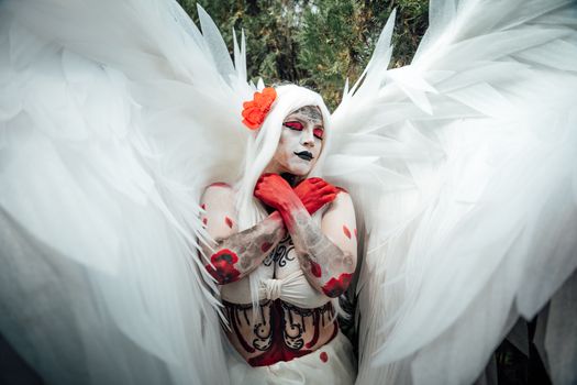 Whimsical portrait of a person in artistic body paint with striking white wings and colorful makeup.