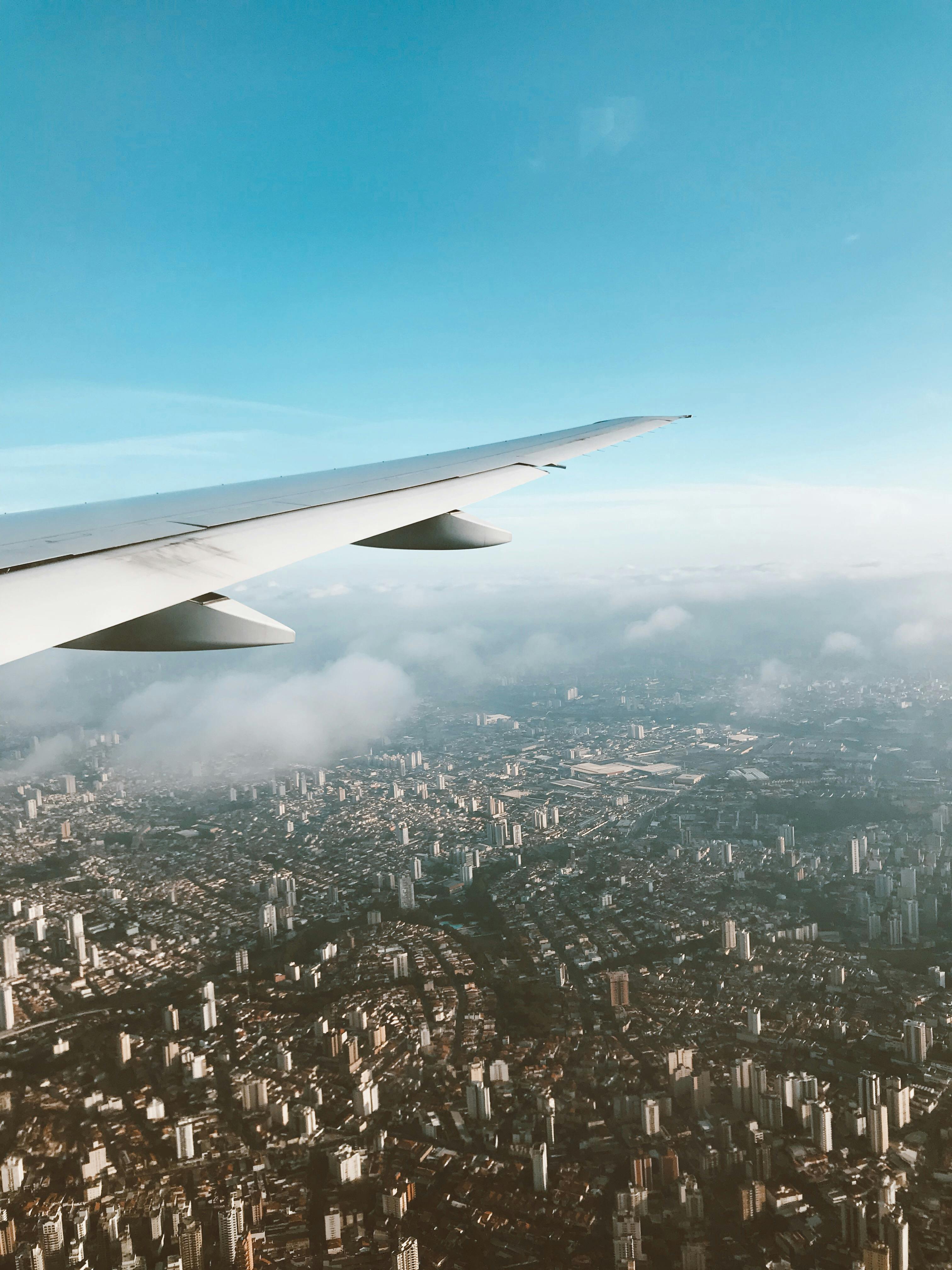 飞机在晴朗的天空下，从上方飞入广阔的城市景观