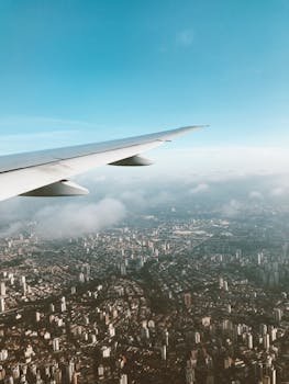 飞机在晴朗的天空下，从上方飞入广阔的城市景观