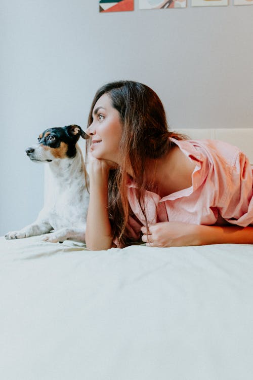 Woman Lying Down with Dog in Bed