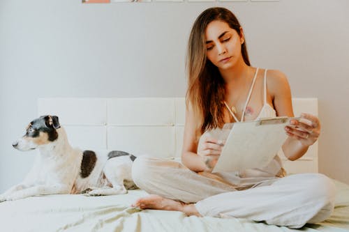 Woman Sitting with Dog on Bed