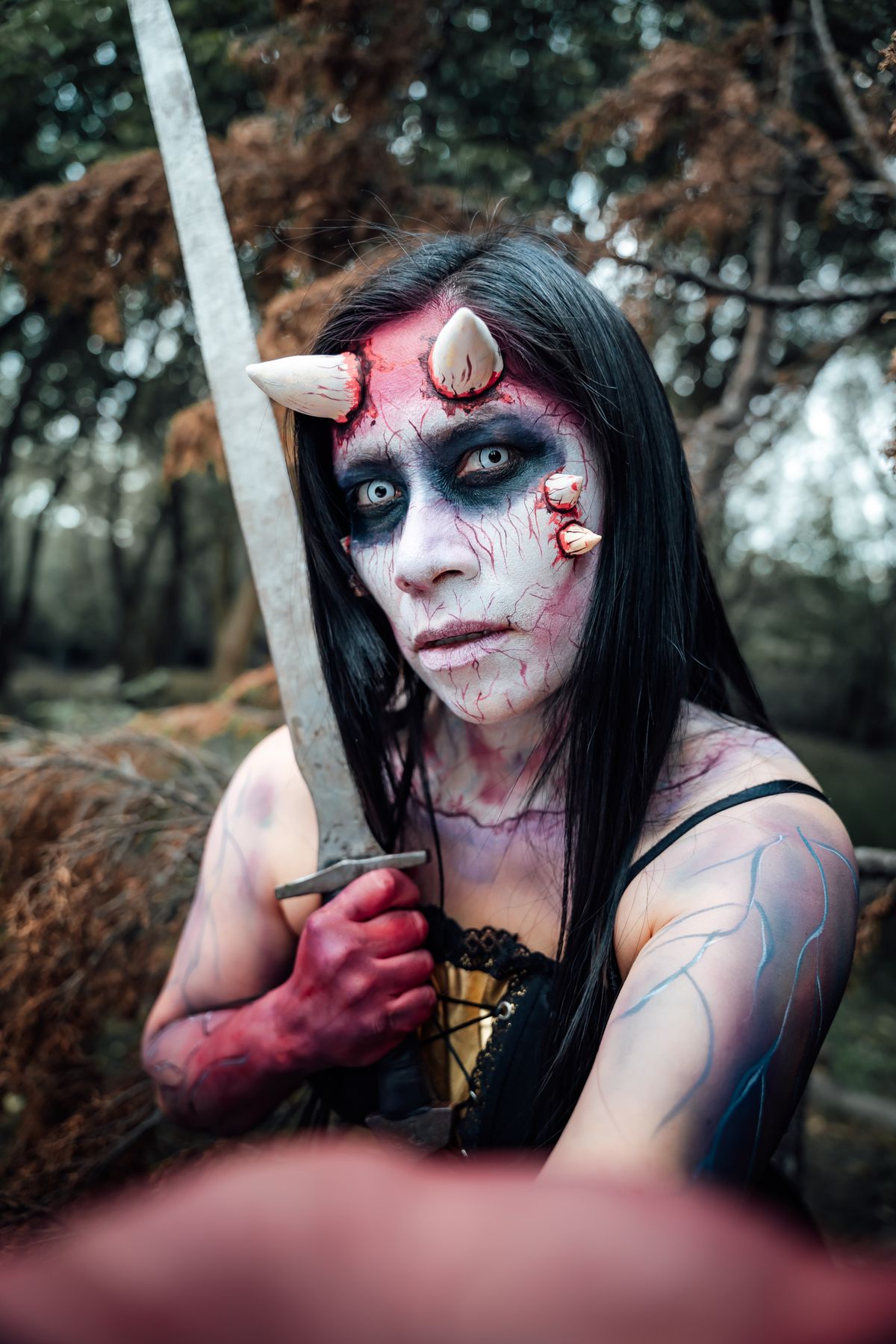 Dark dramatic cosplay portrait of a woman with horns and a sword