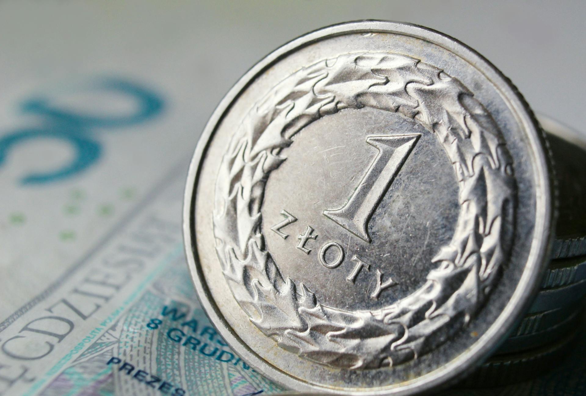 Macro shot of a 1 zloty Polish coin on a banknote, highlighting currency details.