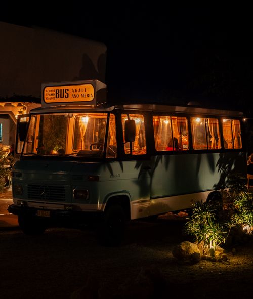 Free A retro-style vintage bus with warm lights is parked outdoors at night, evoking a nostalgic feel. Stock Photo