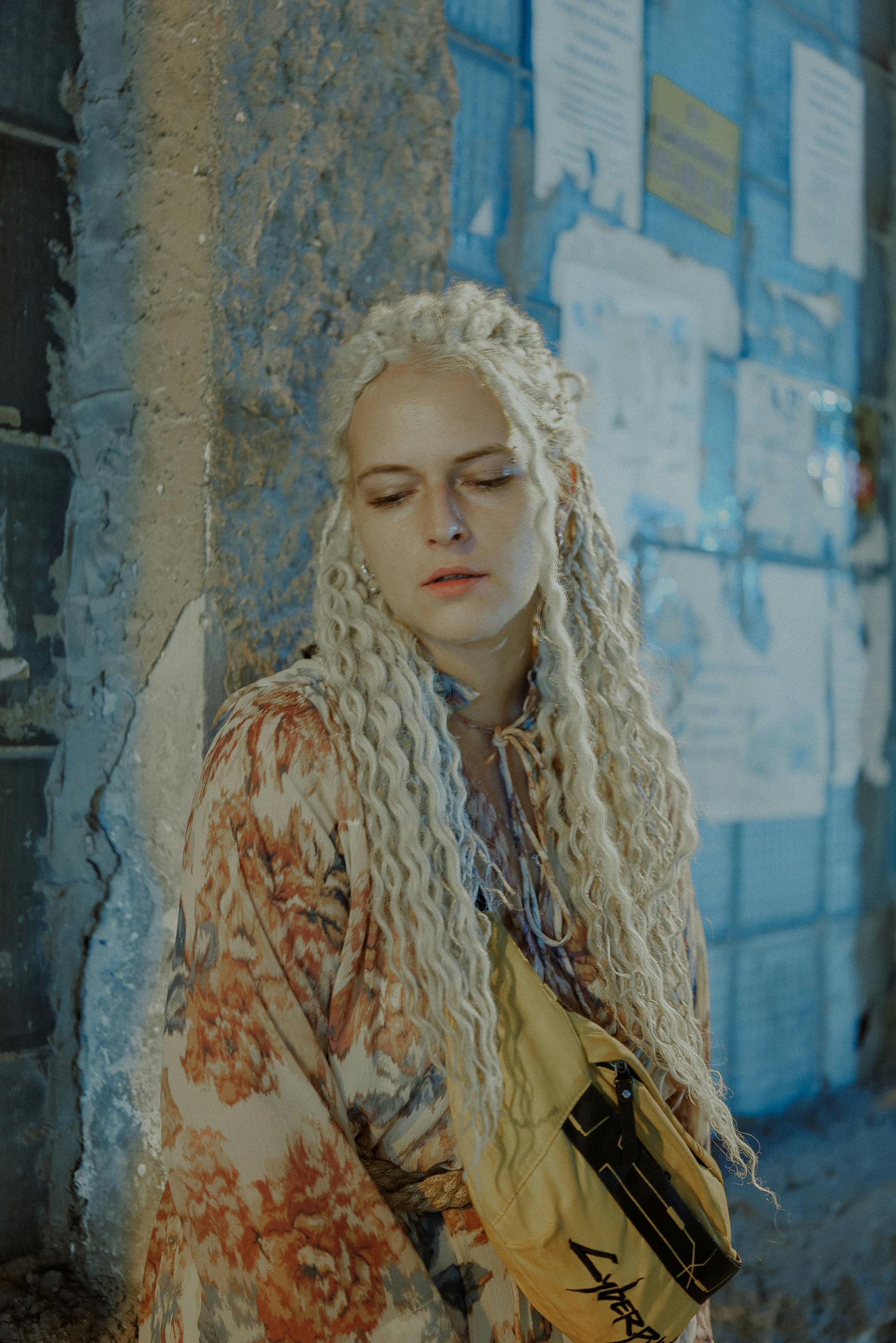 A contemplative blonde woman against a textured wall in Baku.