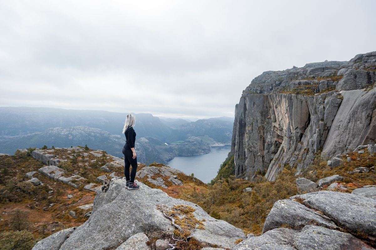 A woman on a misty Norwegian cliff overlooking a fjord