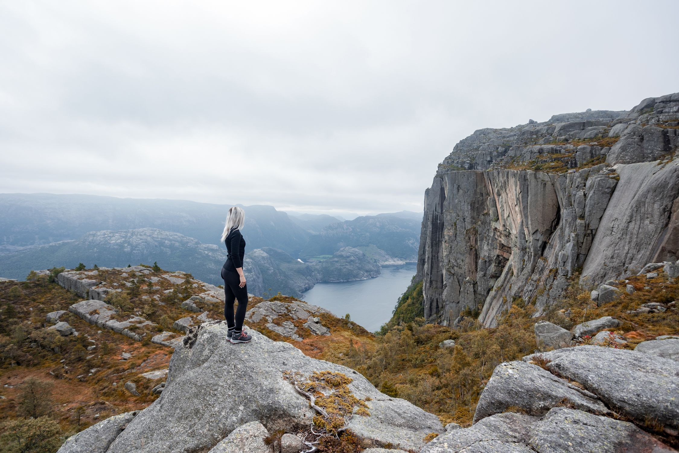 a girl standing on the edge of the cliff in the mountains on a hike in ...