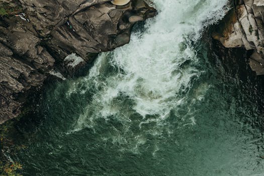 Dynamic aerial shot of a waterfall surrounded by rugged rocks and foaming water.