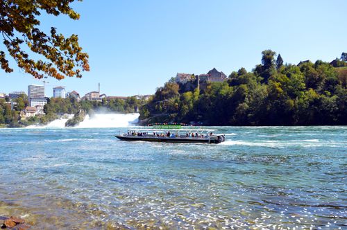 Free Tourists enjoying a boat tour on the Rhine River with Rhine Falls in the background, Switzerland. Stock Photo