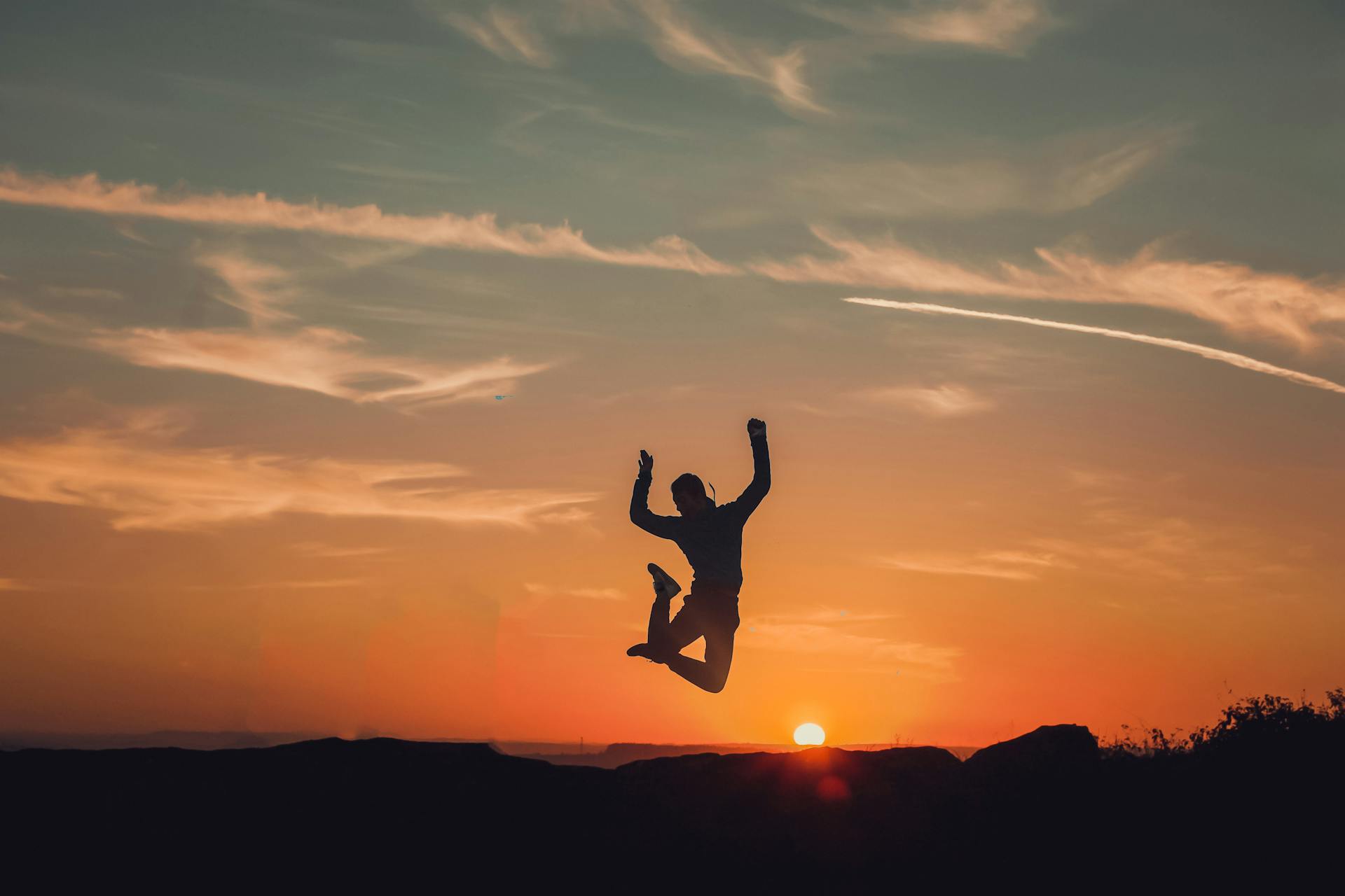 A person silhouetted against a stunning sunset, capturing a moment of freedom and joy.